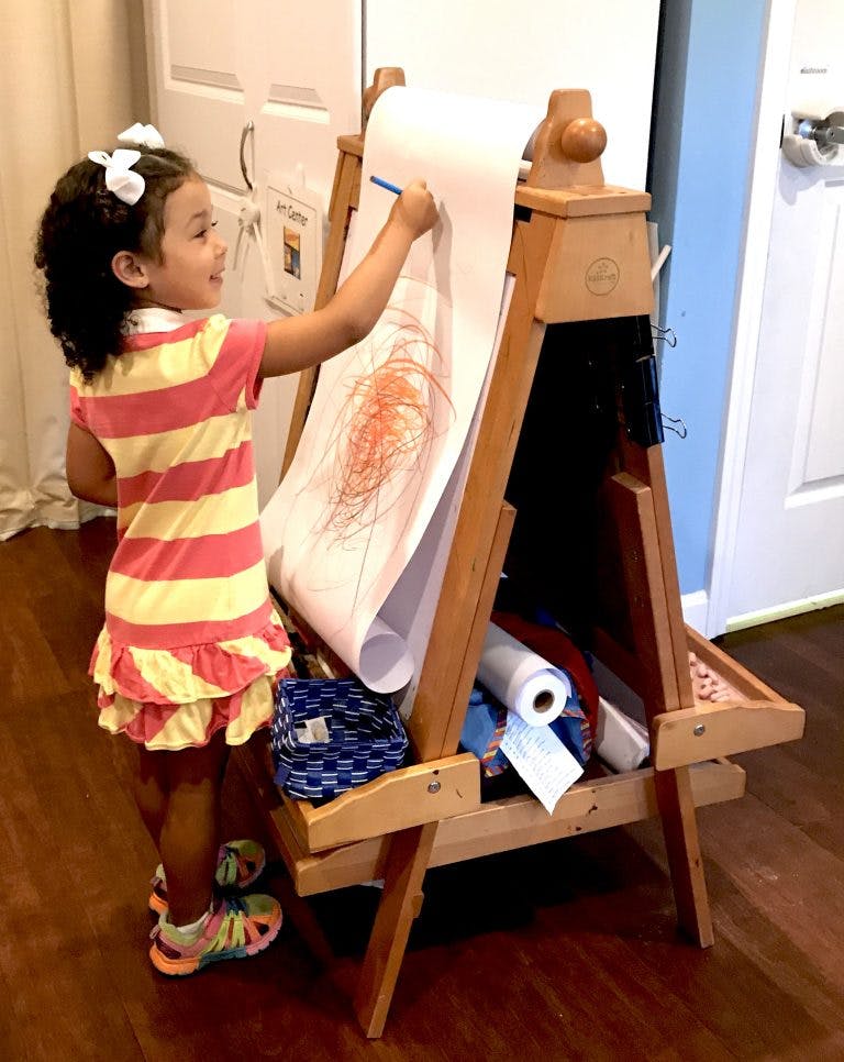 Child drawing on an easel with a roll of paper