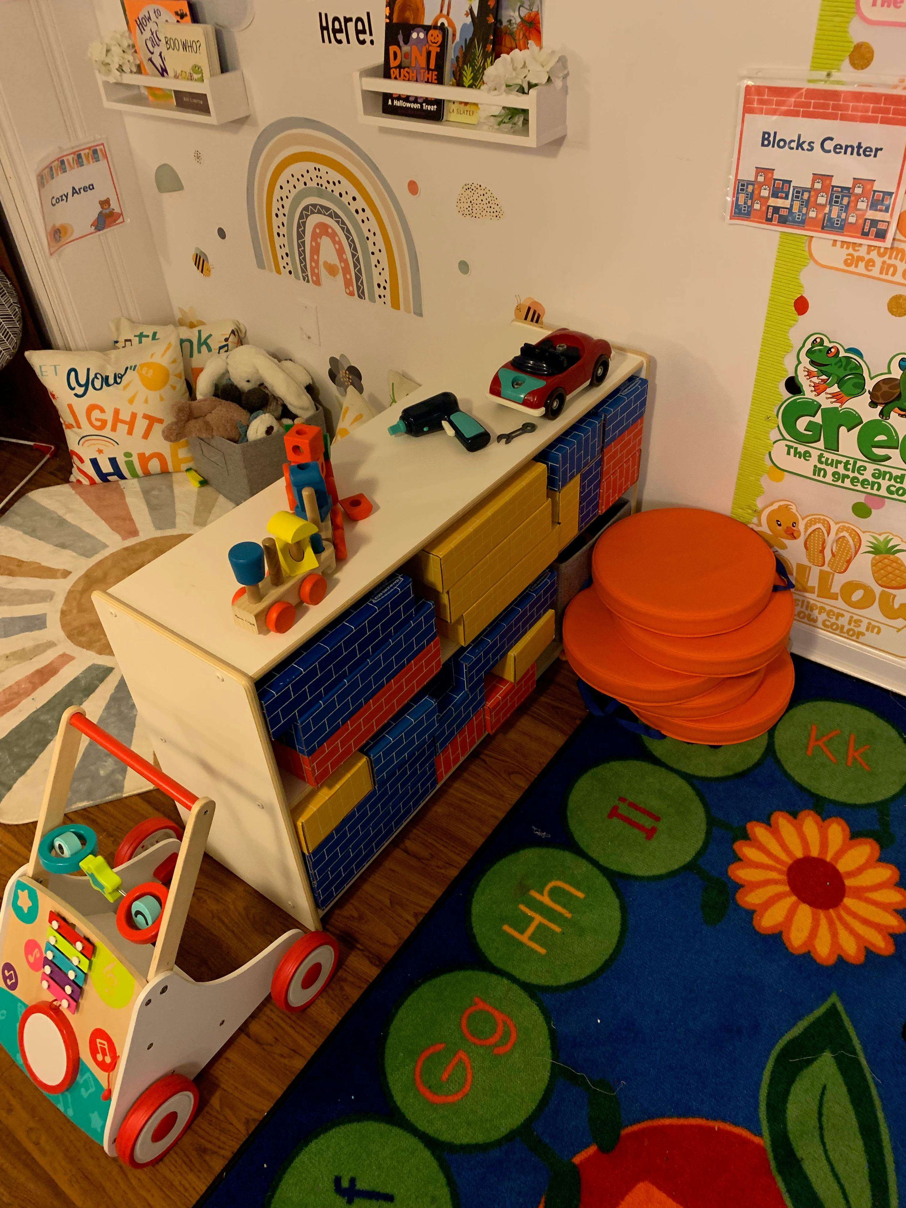 Children's playroom with toys, storage unit, and alphabet rug