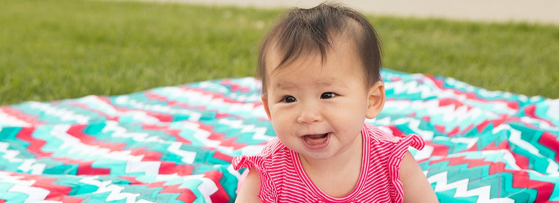 Child sitting on a patterned blanket outdoors