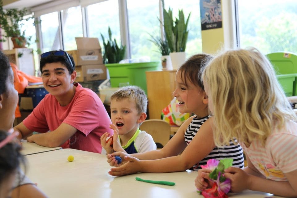 Teen and children at a table with modeling clay