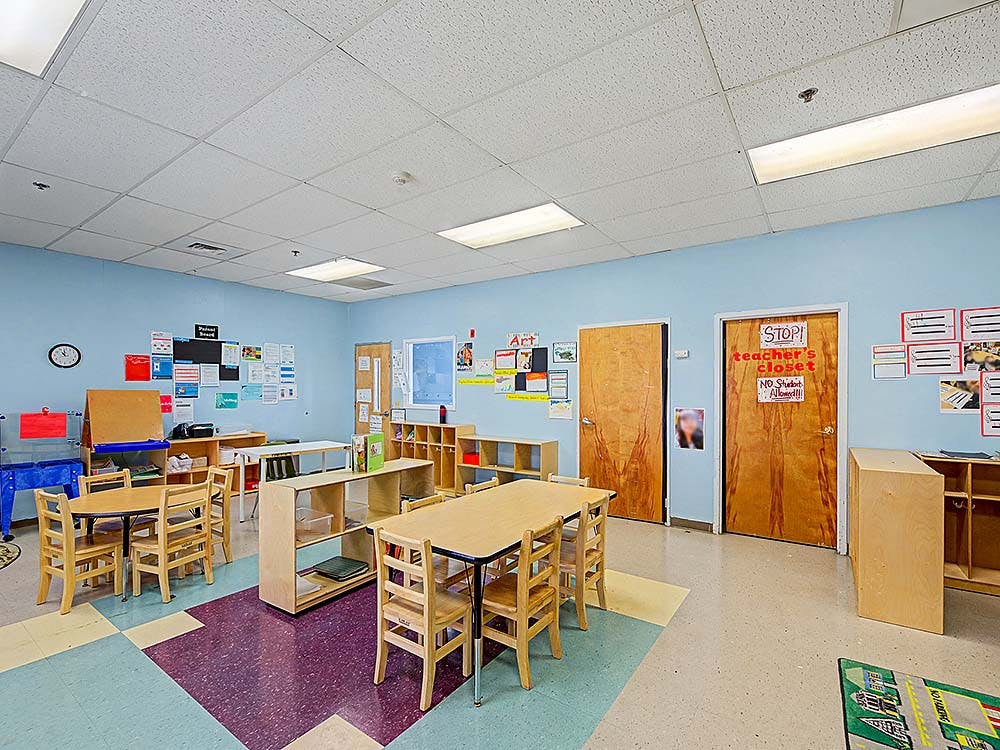Classroom with small tables and chairs, shelves, and art on the walls