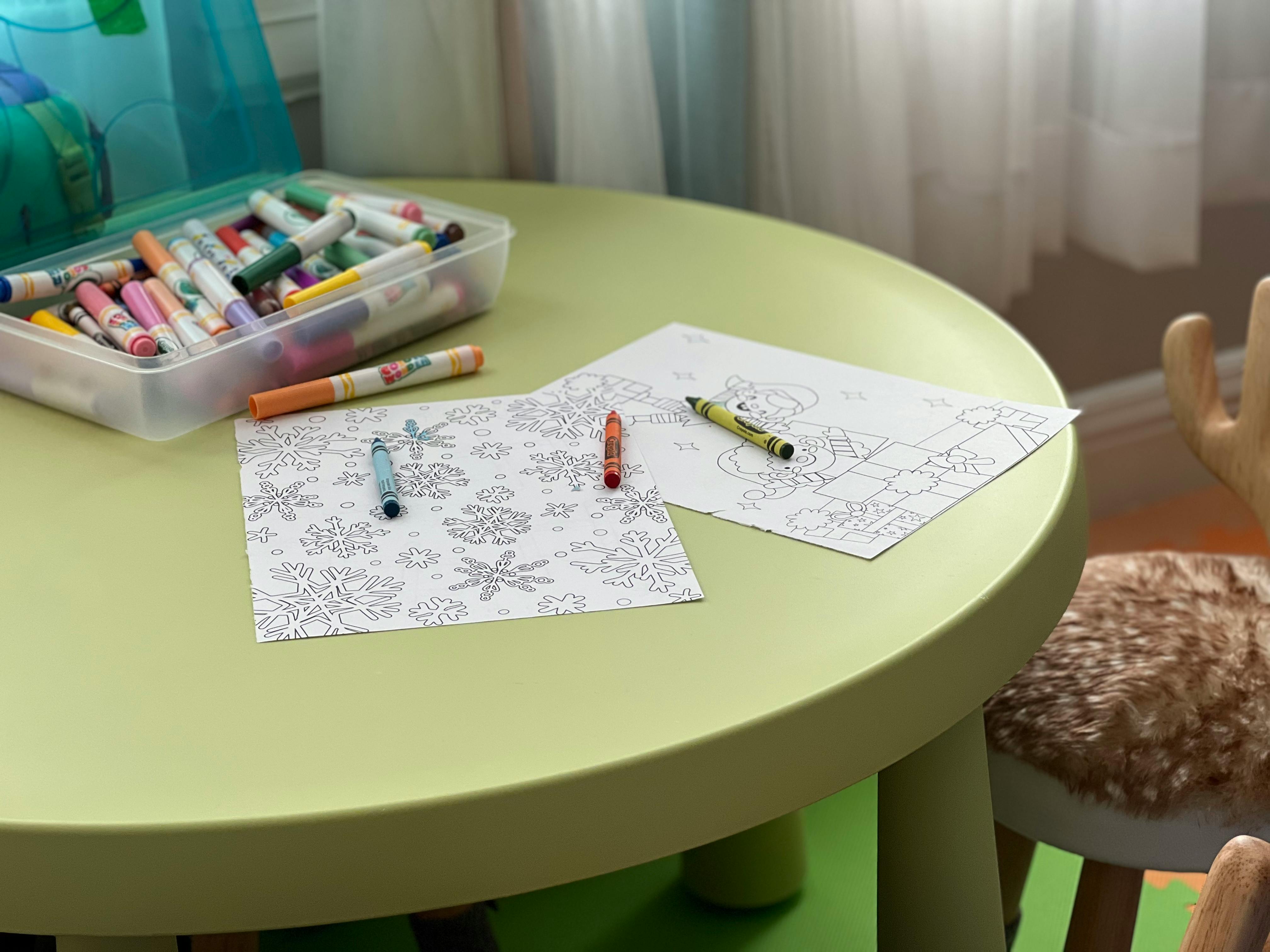Crayons and coloring pages on a green table