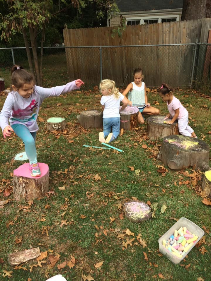 Children playing on tree stumps outdoors