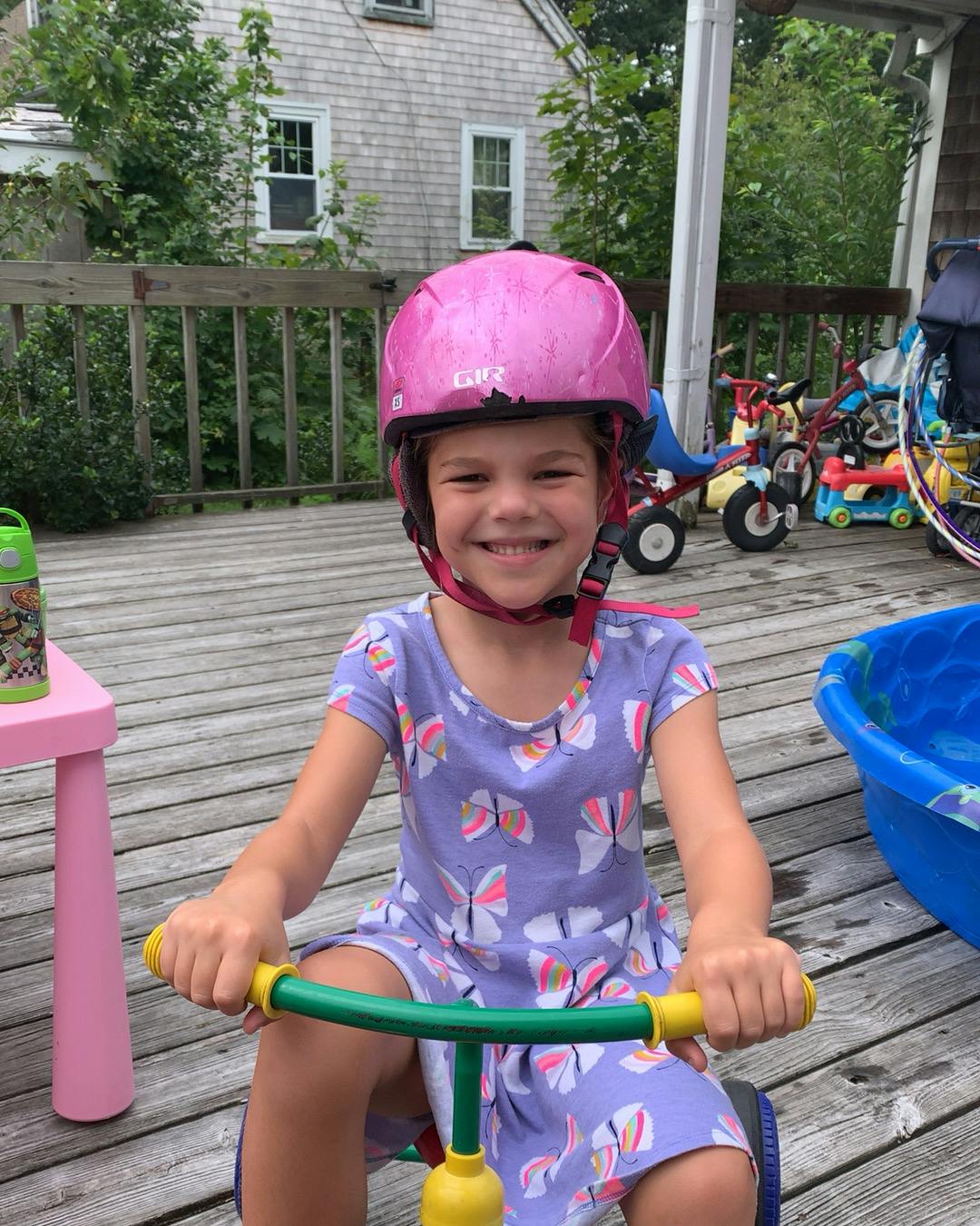 Child in a pink helmet on a tricycle