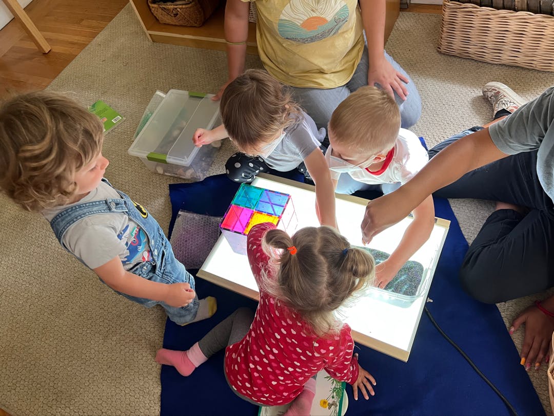 Children playing with colorful blocks on a light table