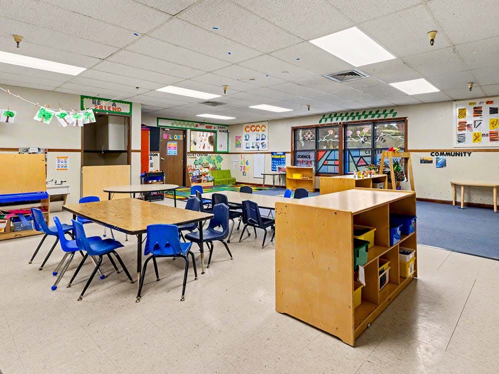 Empty preschool classroom with small tables and chairs