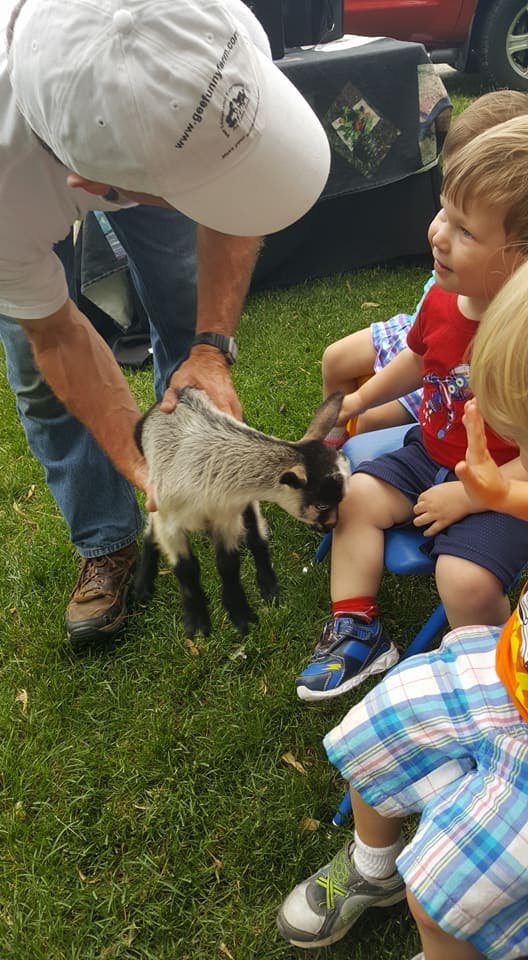 Person holding a small goat near children