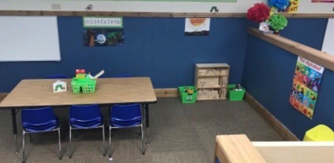 Classroom with a table, three chairs, and various learning materials