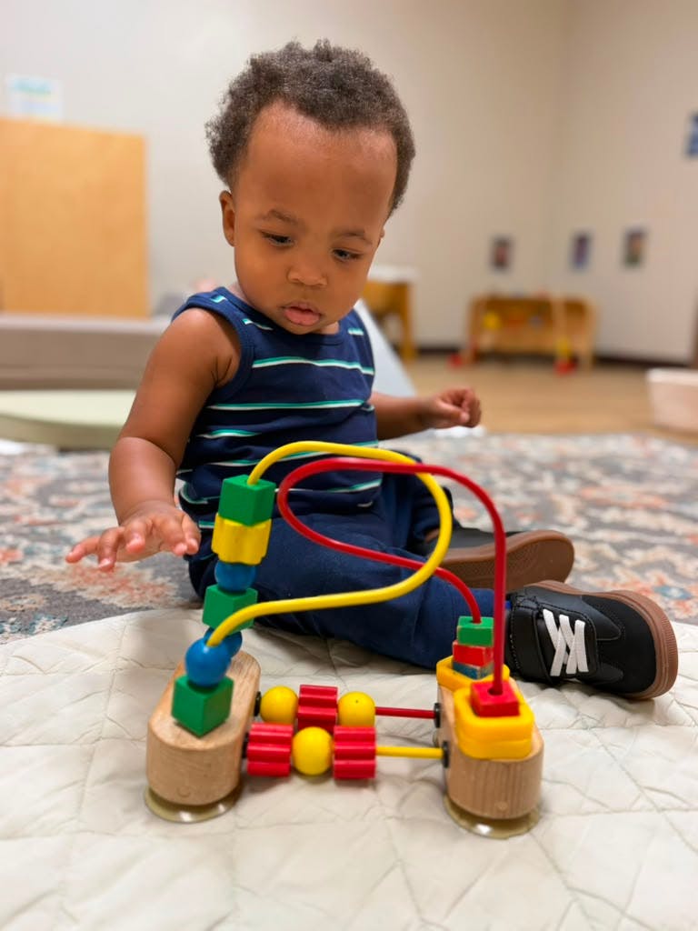 Child playing with a wooden bead maze toy