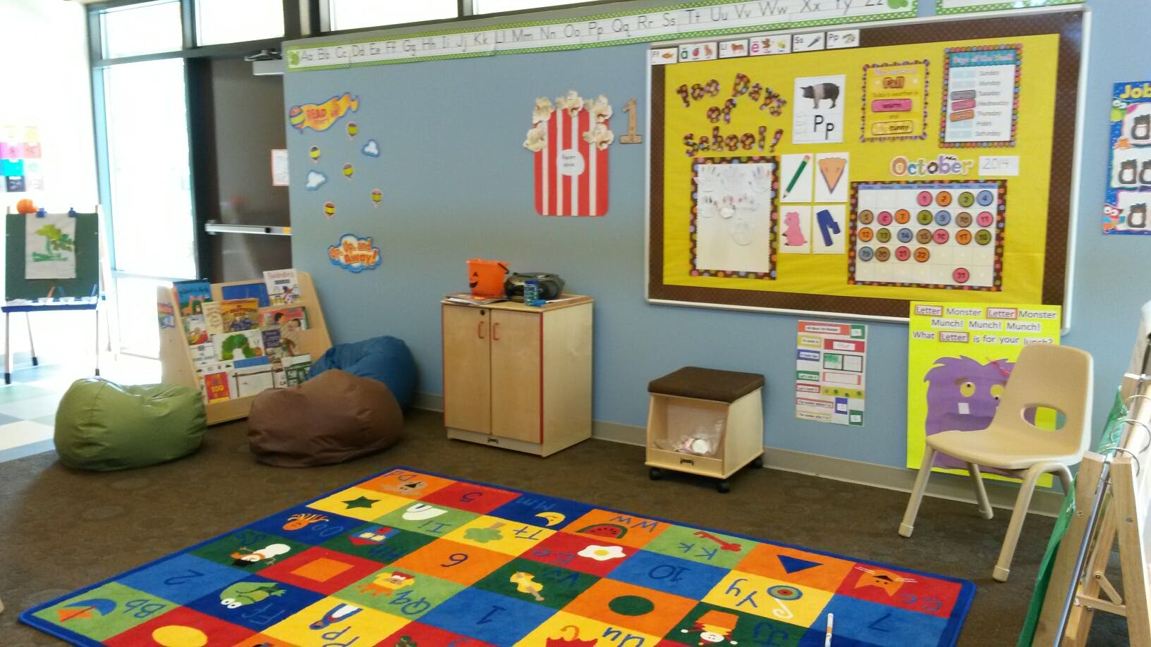 Classroom with colorful rug, beanbags, and bulletin board