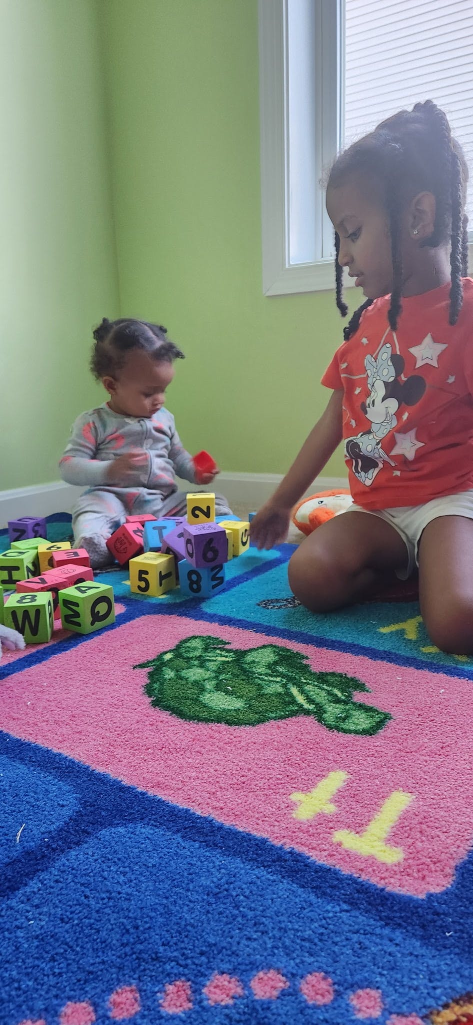 Two children playing with colorful blocks on a rug