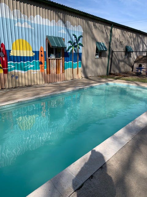 Swimming pool next to a building with a beach mural