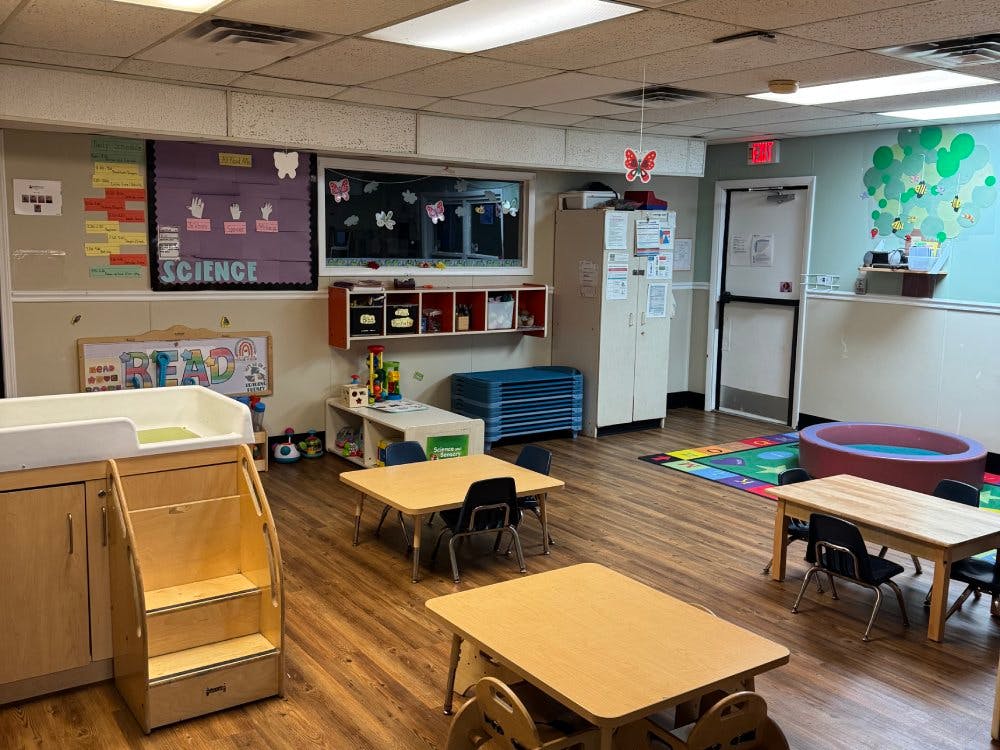 Empty children's classroom with small tables, chairs, and play equipment