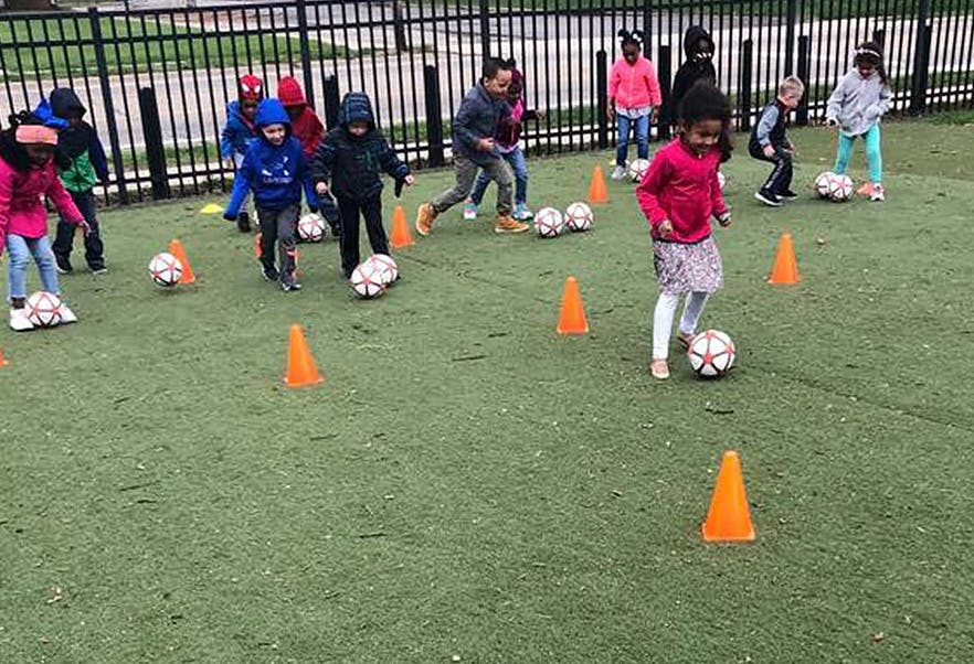Children playing soccer with cones on a green field