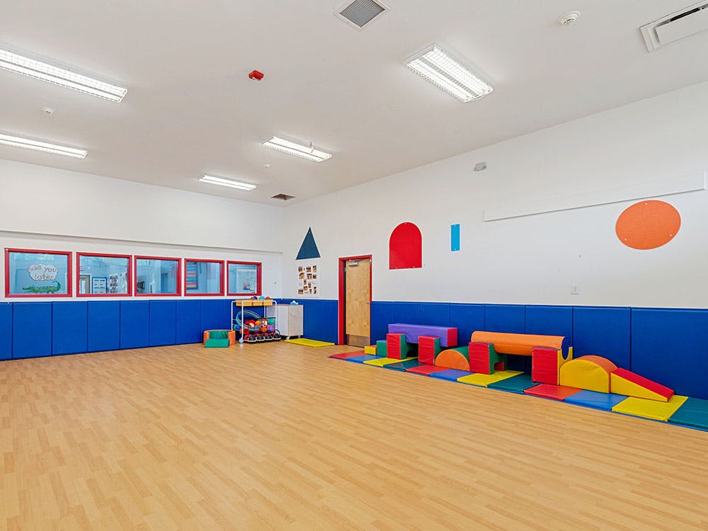 An empty children's play area with soft play equipment on mats and padded walls
