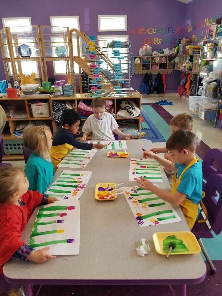 Children painting at a table in a classroom