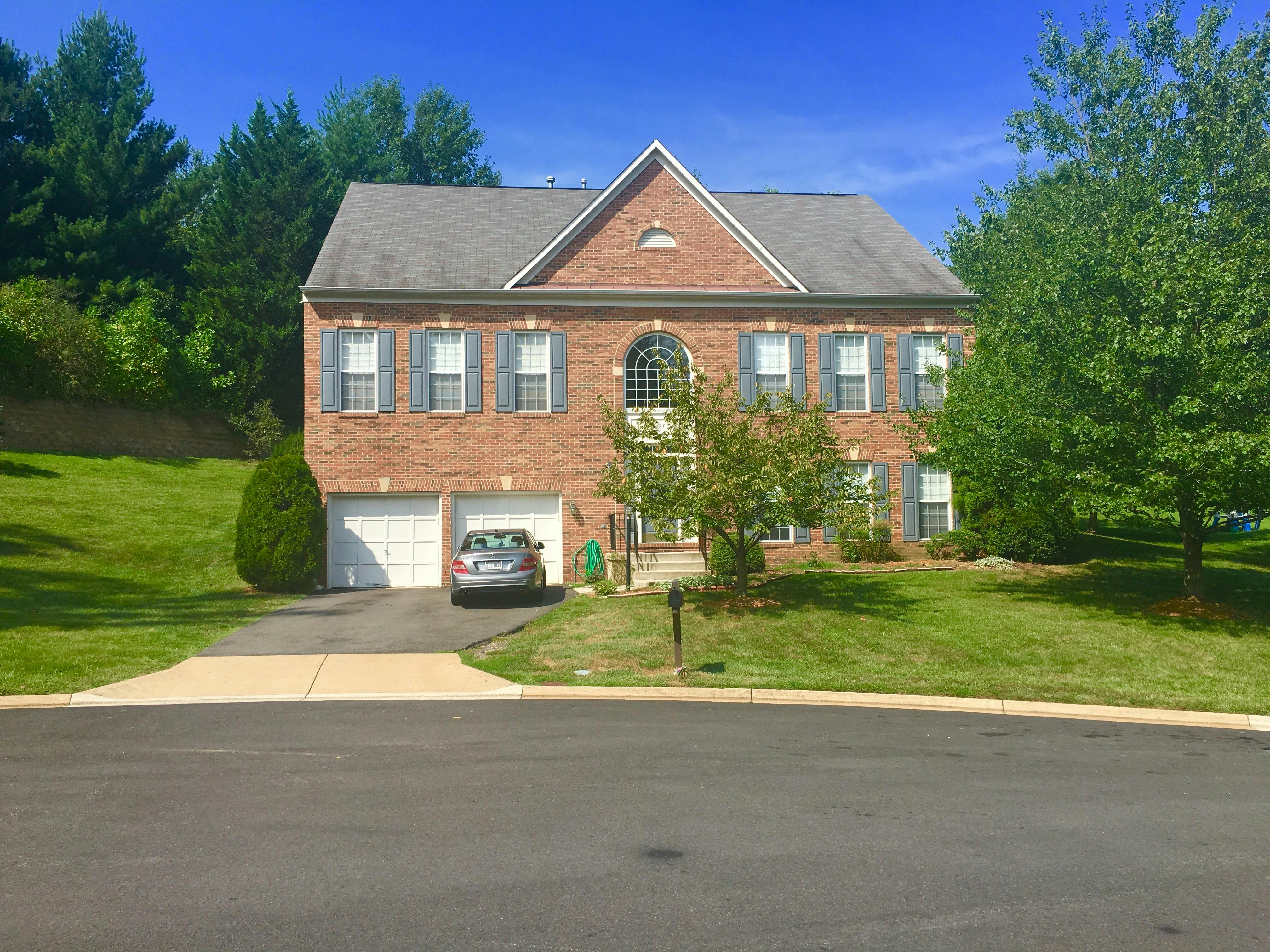 Brick house with two garage doors and a car in the driveway