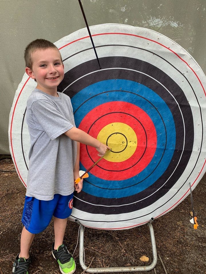 Child pointing at an arrow in an archery target