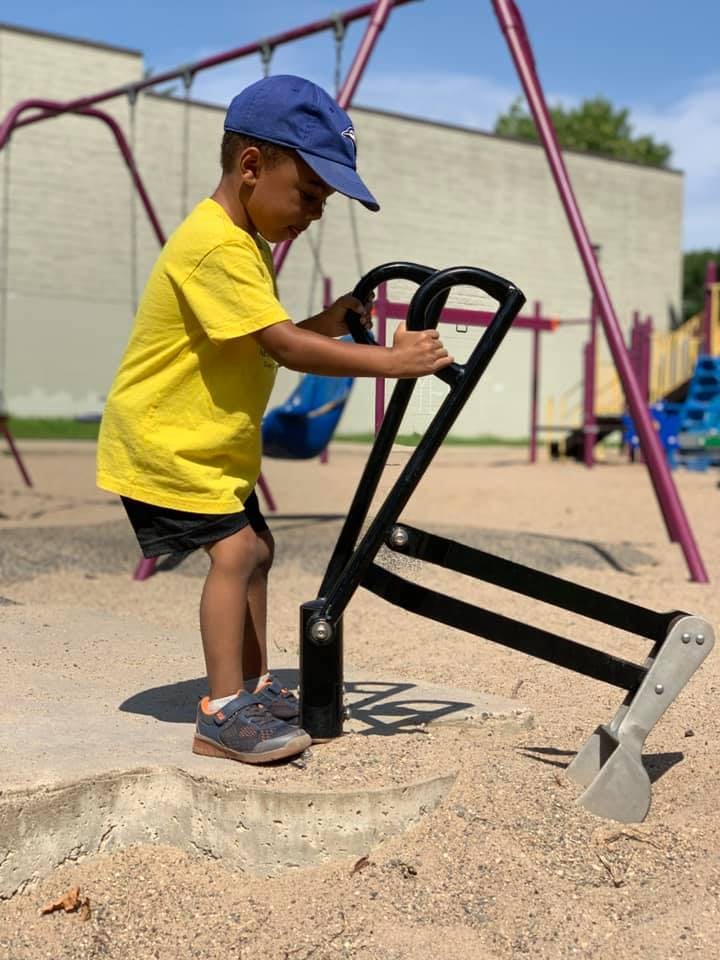 Child playing with a digger toy in a sandbox