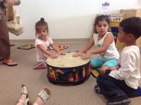 Three children playing a drum