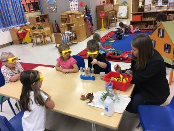 Adult and children in safety goggles at a table with science experiment supplies