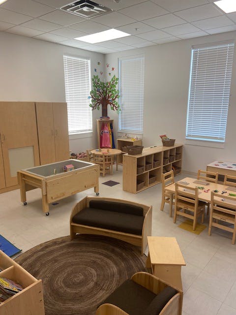 Classroom with wooden furniture, including tables, chairs, and storage units