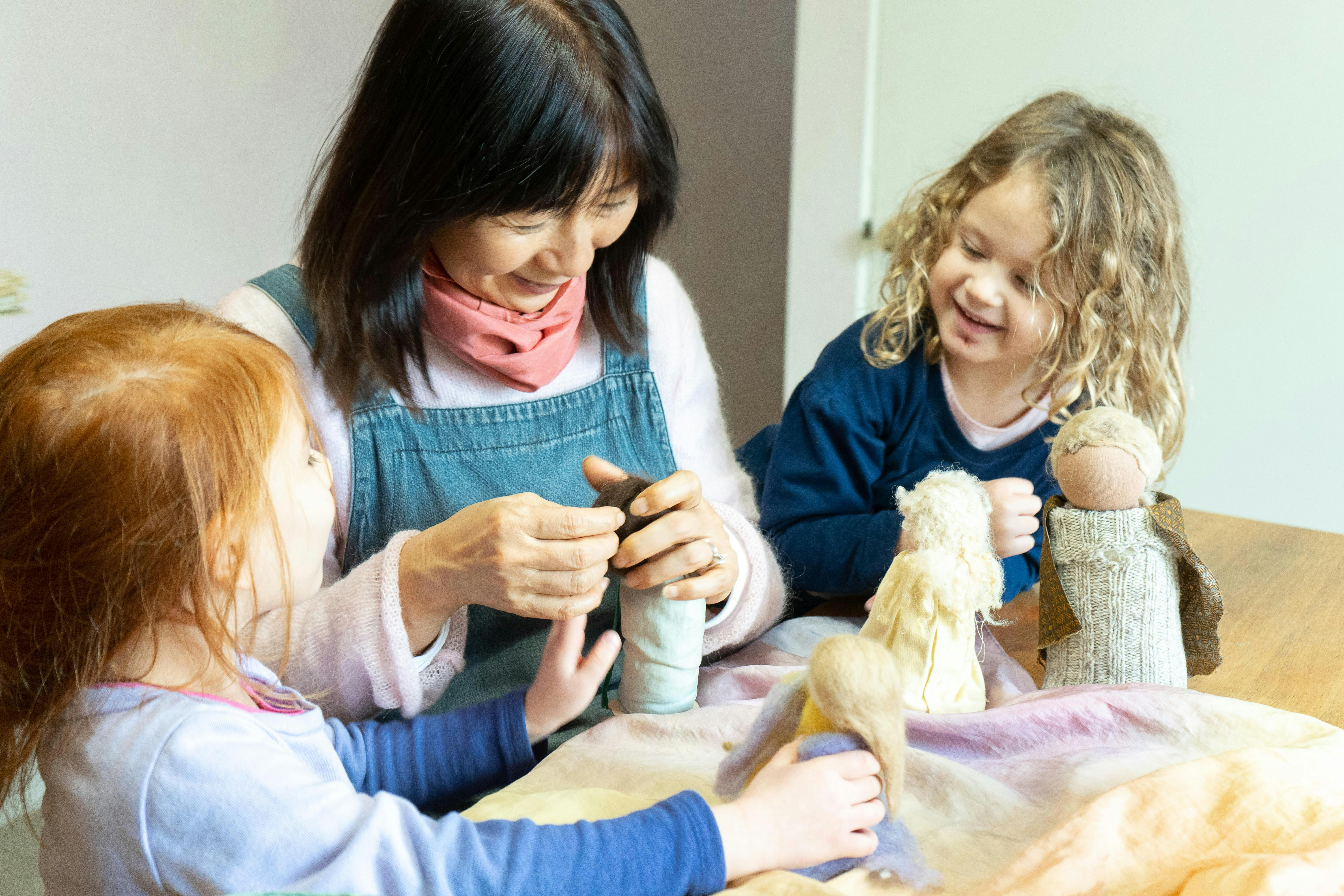 Person and two children playing with dolls