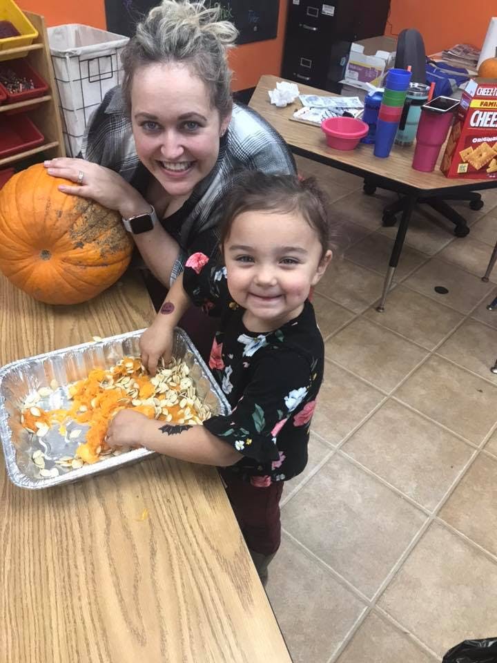 Person and child carving a pumpkin, scooping out seeds and pulp