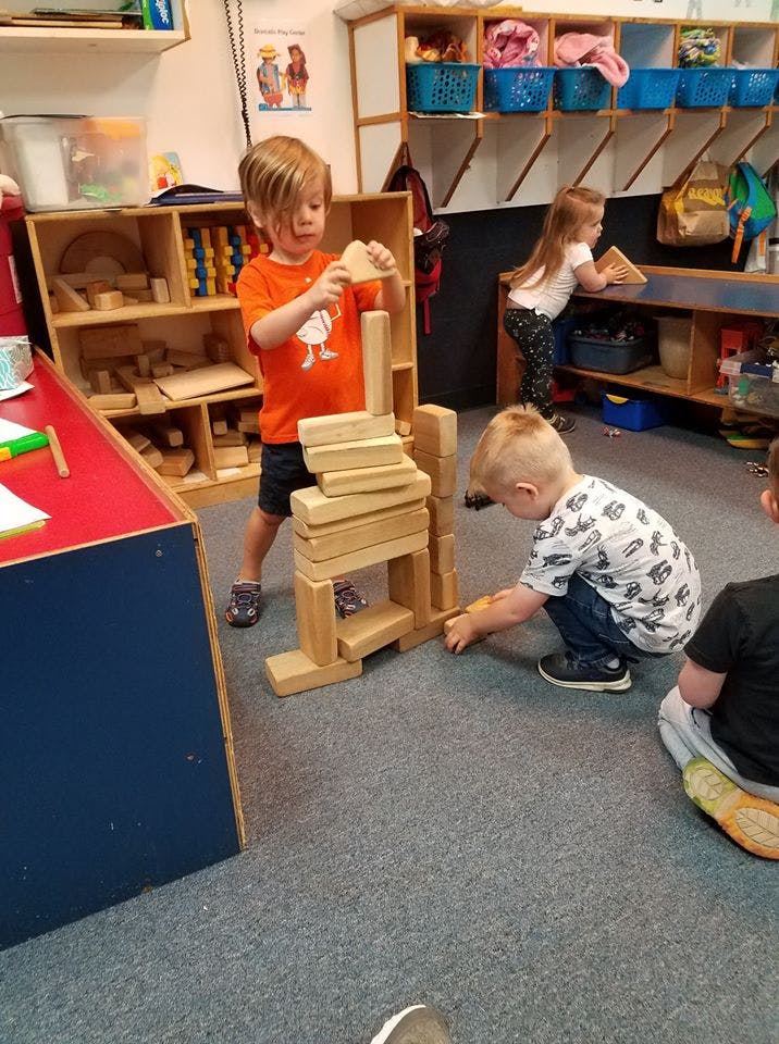 Children playing with wooden blocks in a classroom