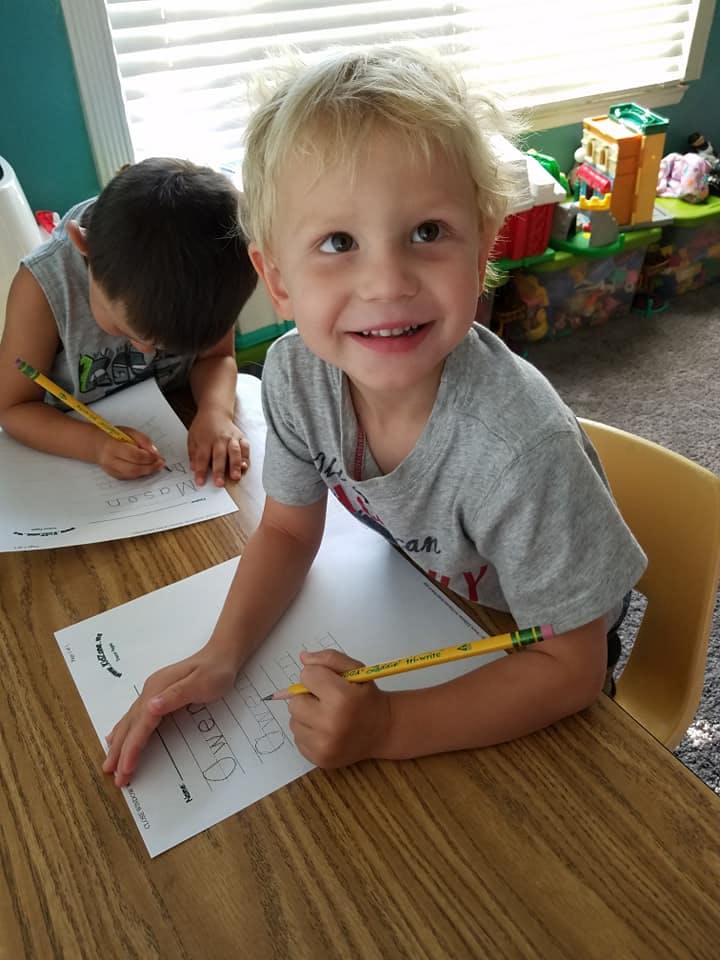 Two children drawing with pencils at a table