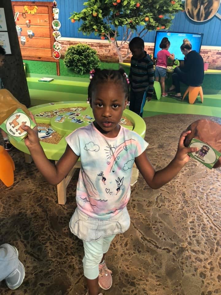 Child holding two cards with images on a playground