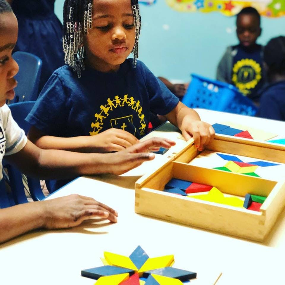 Child and person playing with colorful geometric shapes at a table