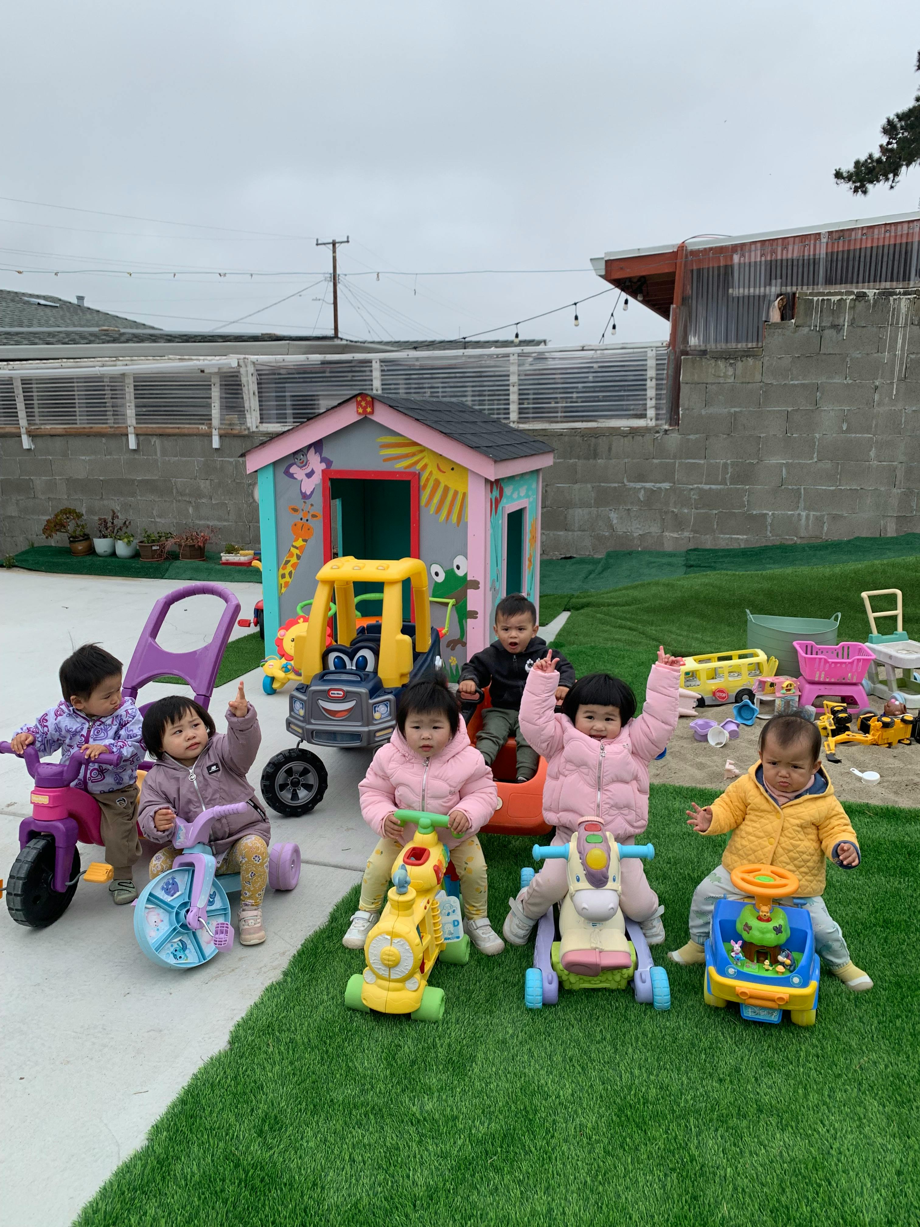 Group of young children playing on ride-on toys in an outdoor area