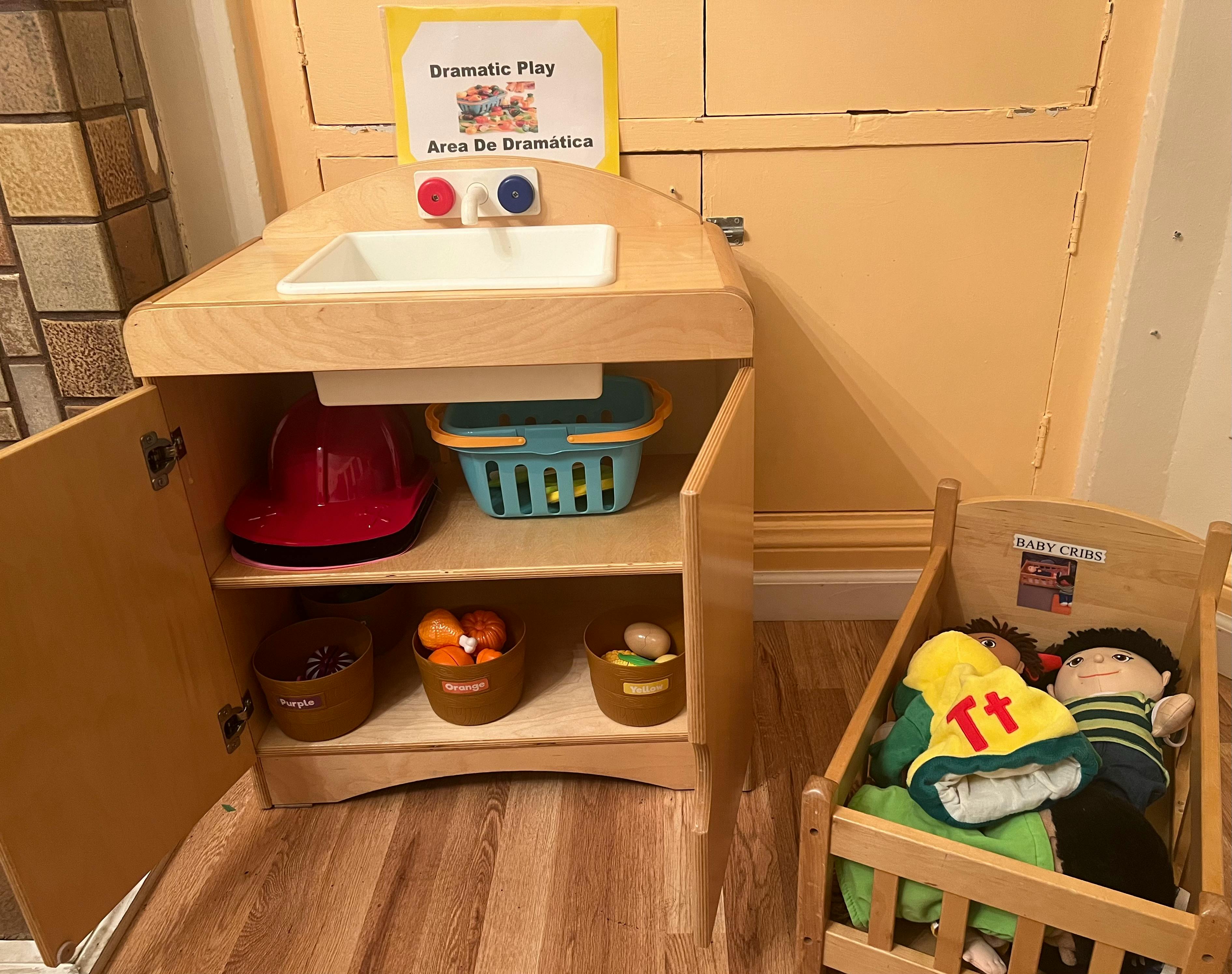 Play kitchen with toy food and a doll in a crib