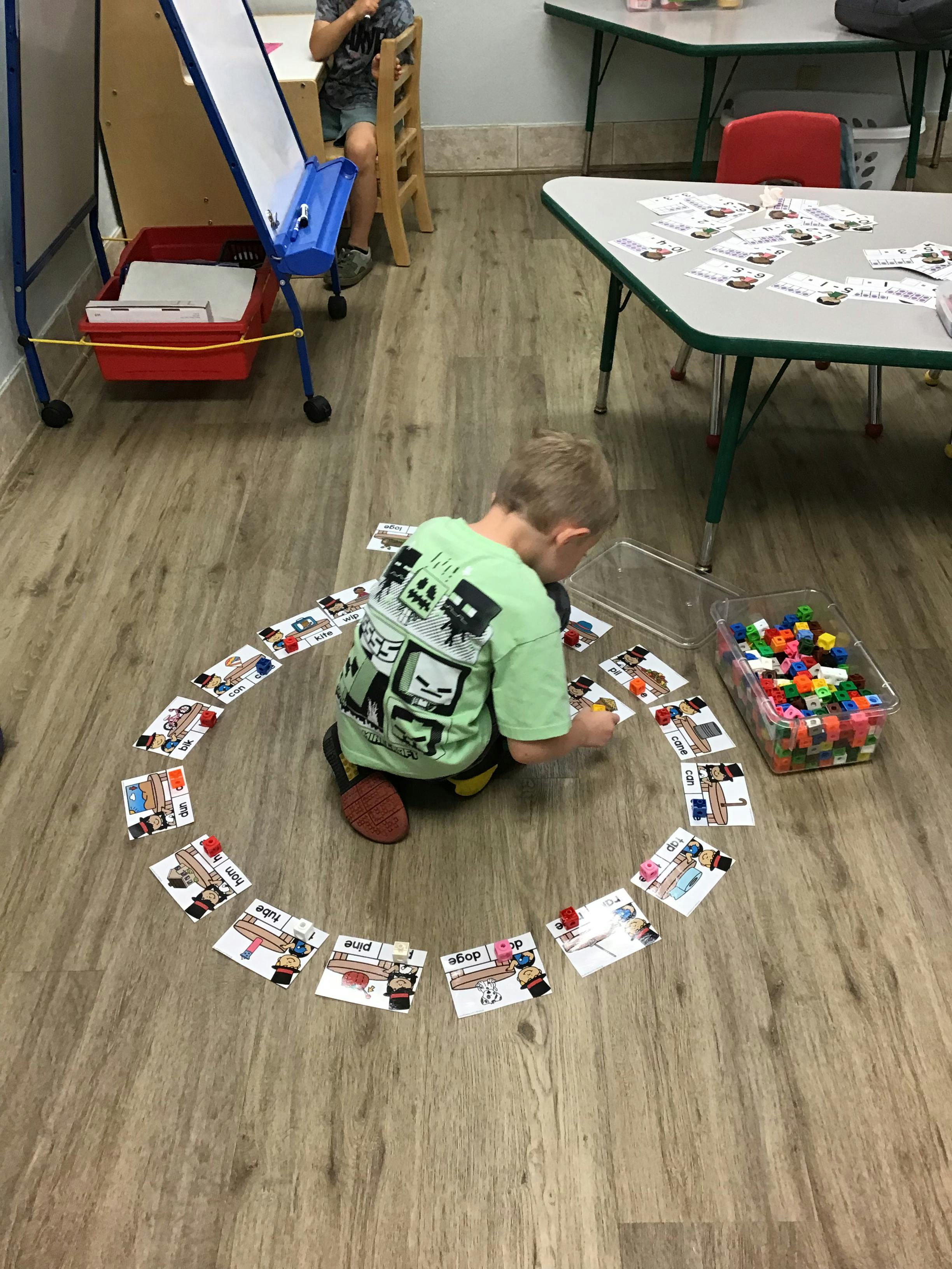 Child on floor arranging cards in a circle