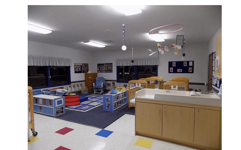 Childcare room with cribs, play mat, and changing table