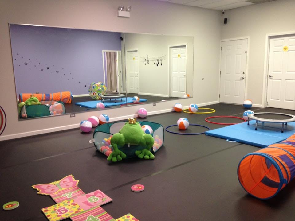 Playroom with a large mirror, a green frog toy, balls, hoops, and a tunnel