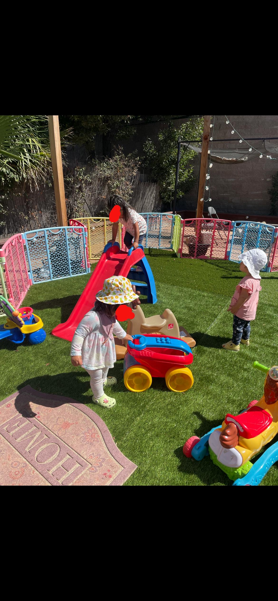 Children playing with toys and a slide on green turf