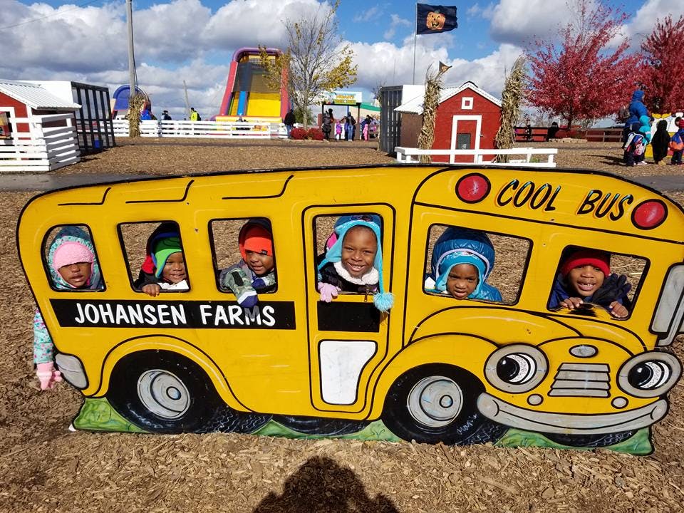Children looking out of a yellow school bus cutout at Johansen Farms
