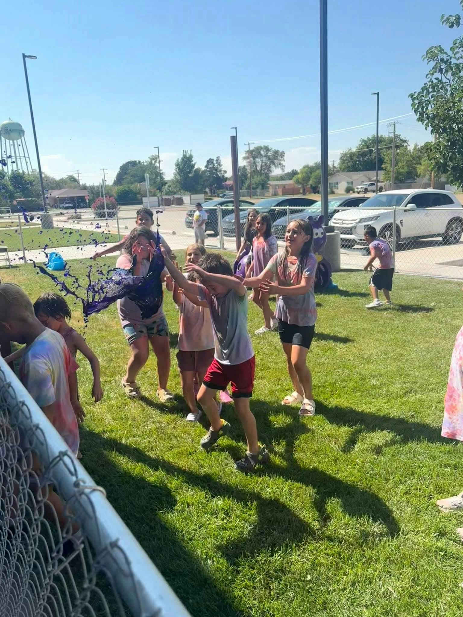 People playing with purple liquid splashing in a grassy area