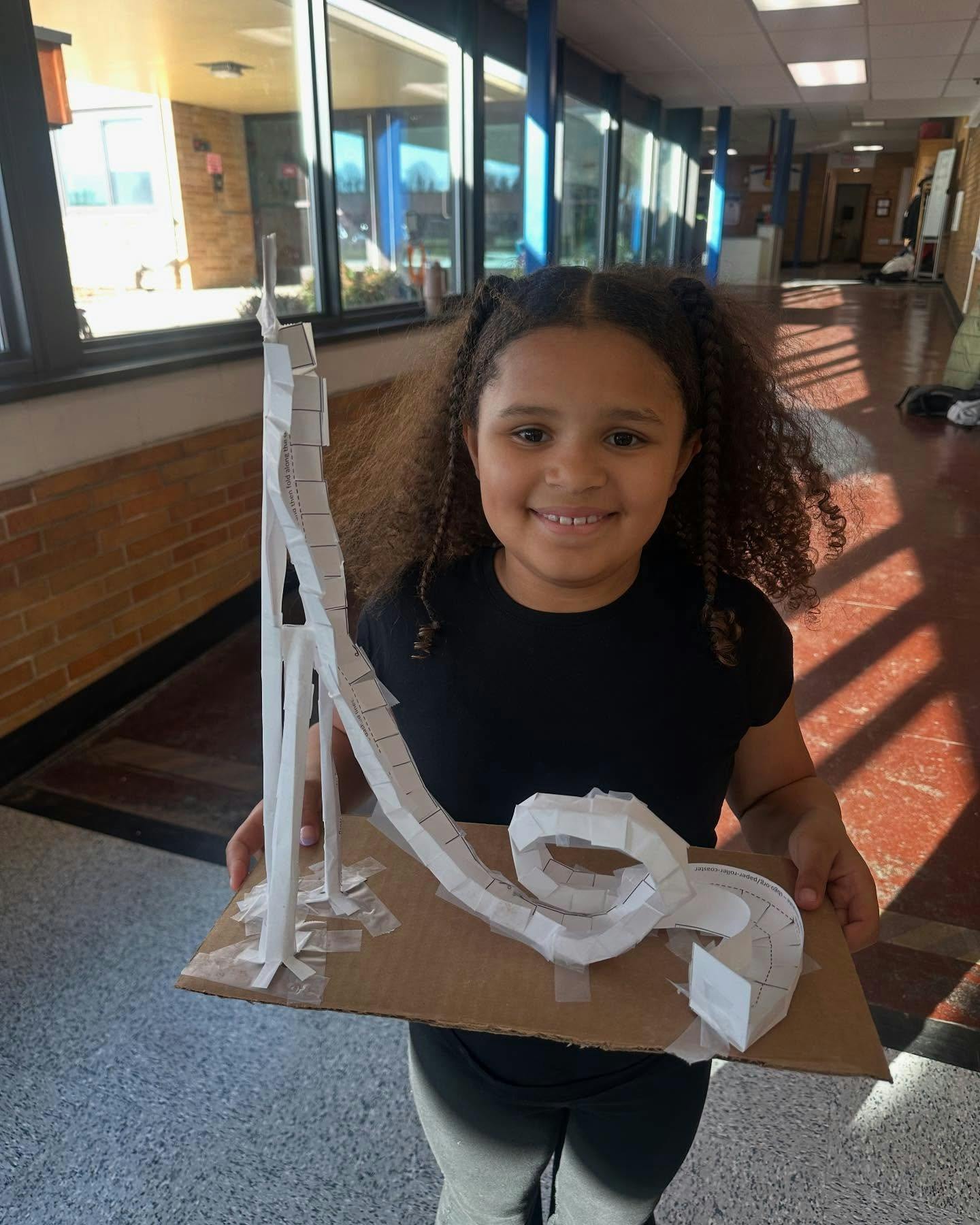 Child holding a handmade roller coaster model