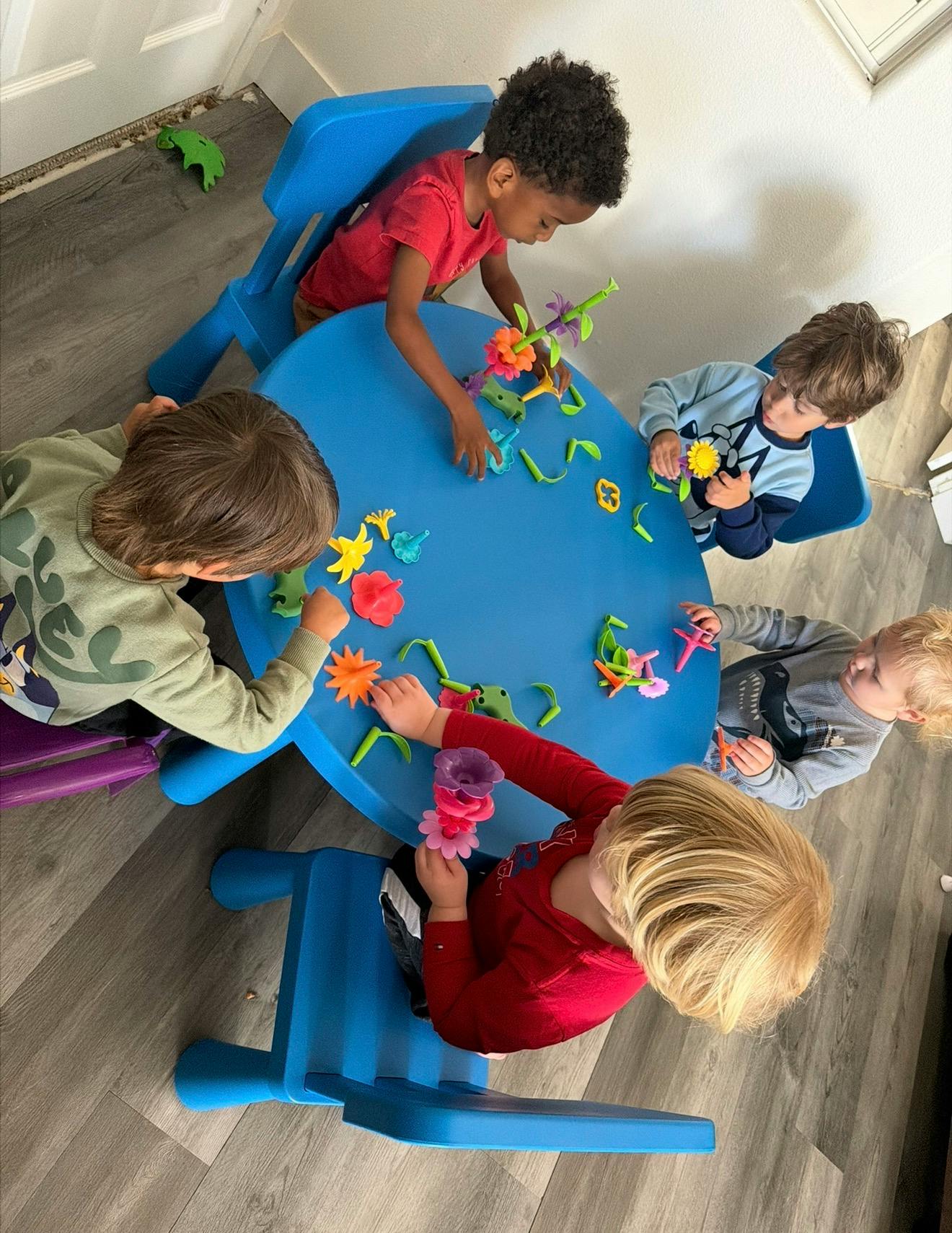 Four children playing with colorful building blocks at a blue table