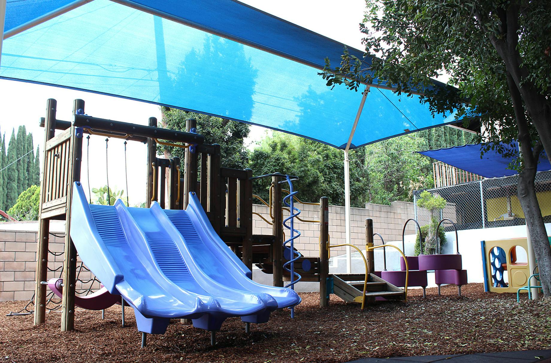 Playground with blue slides and shade canopy