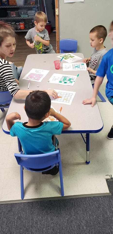 Adult and children at a table with papers and markers