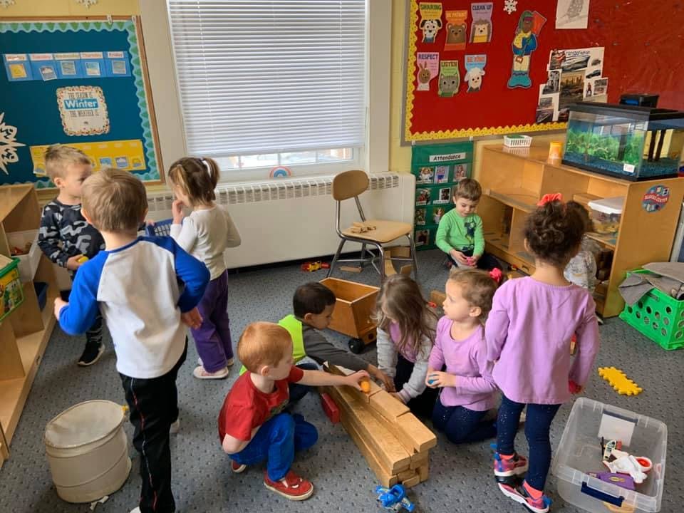 Children playing with wooden blocks and toys in a classroom