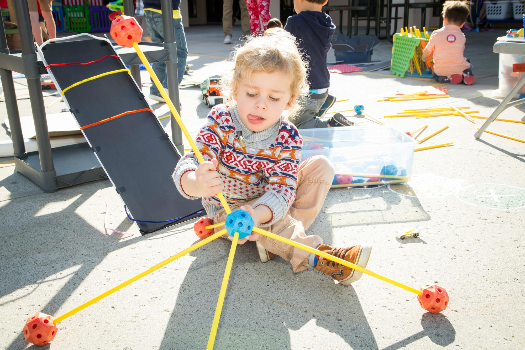 Child sitting on the ground playing with a building toy