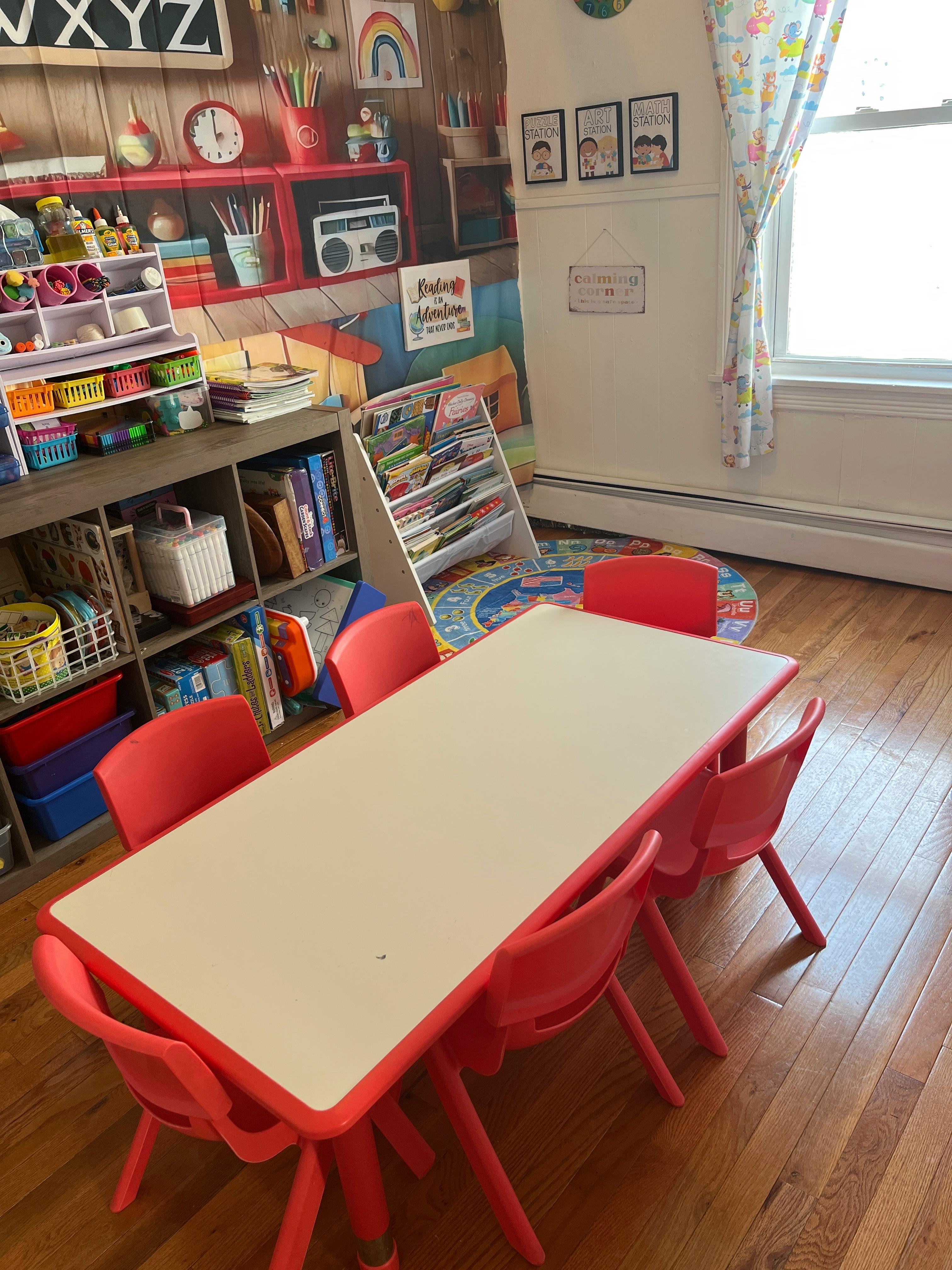 Child's play area with a red table and chairs, shelves with toys and books