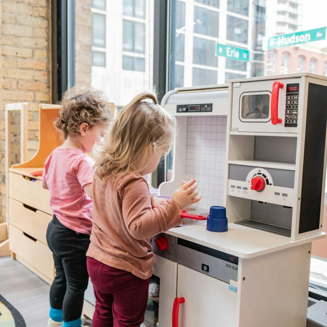 Two children playing with a toy kitchen set