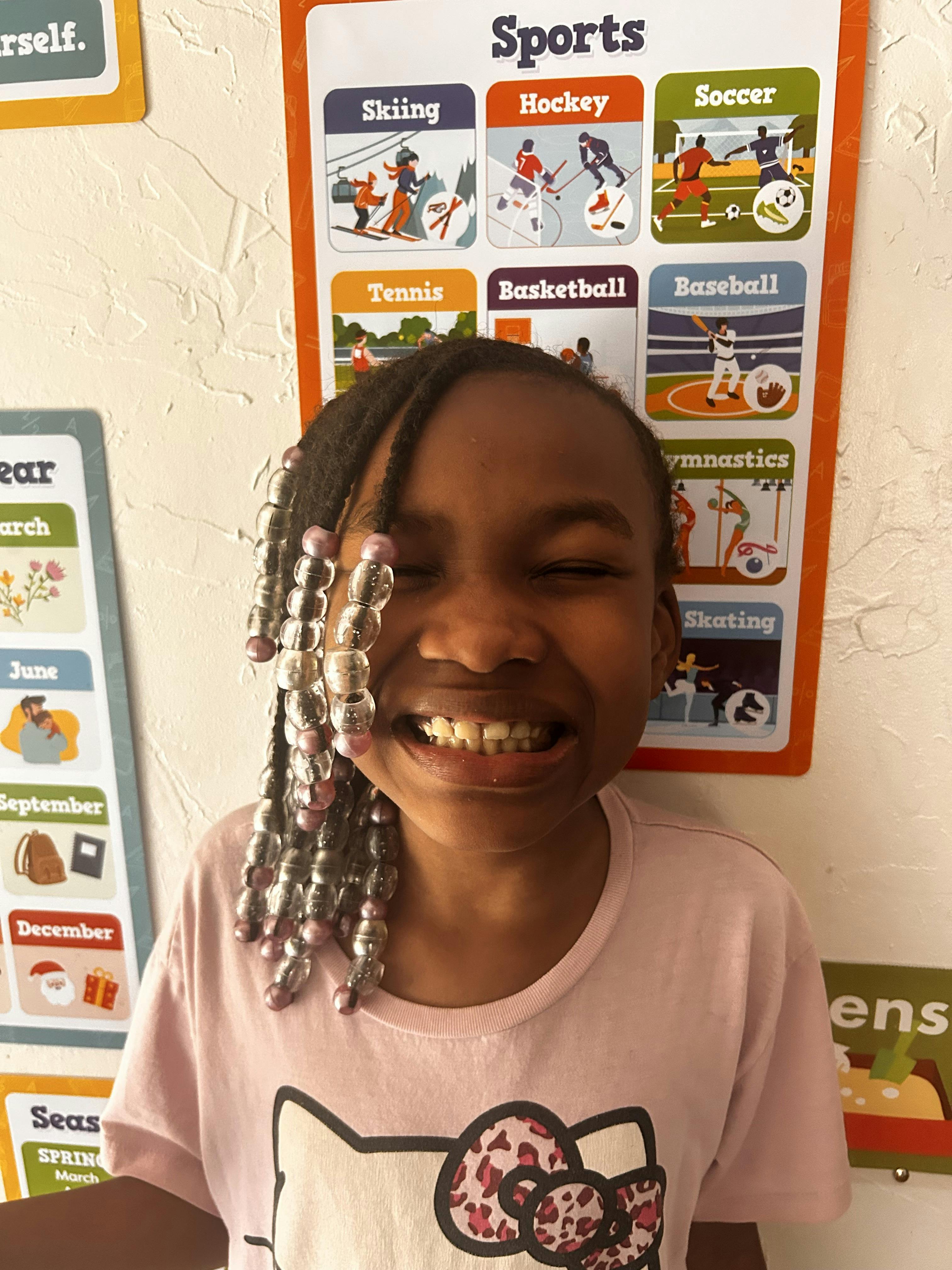 Child smiling in front of a sports poster