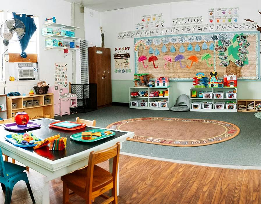 Classroom interior with tables, chairs, toys, and educational wall displays